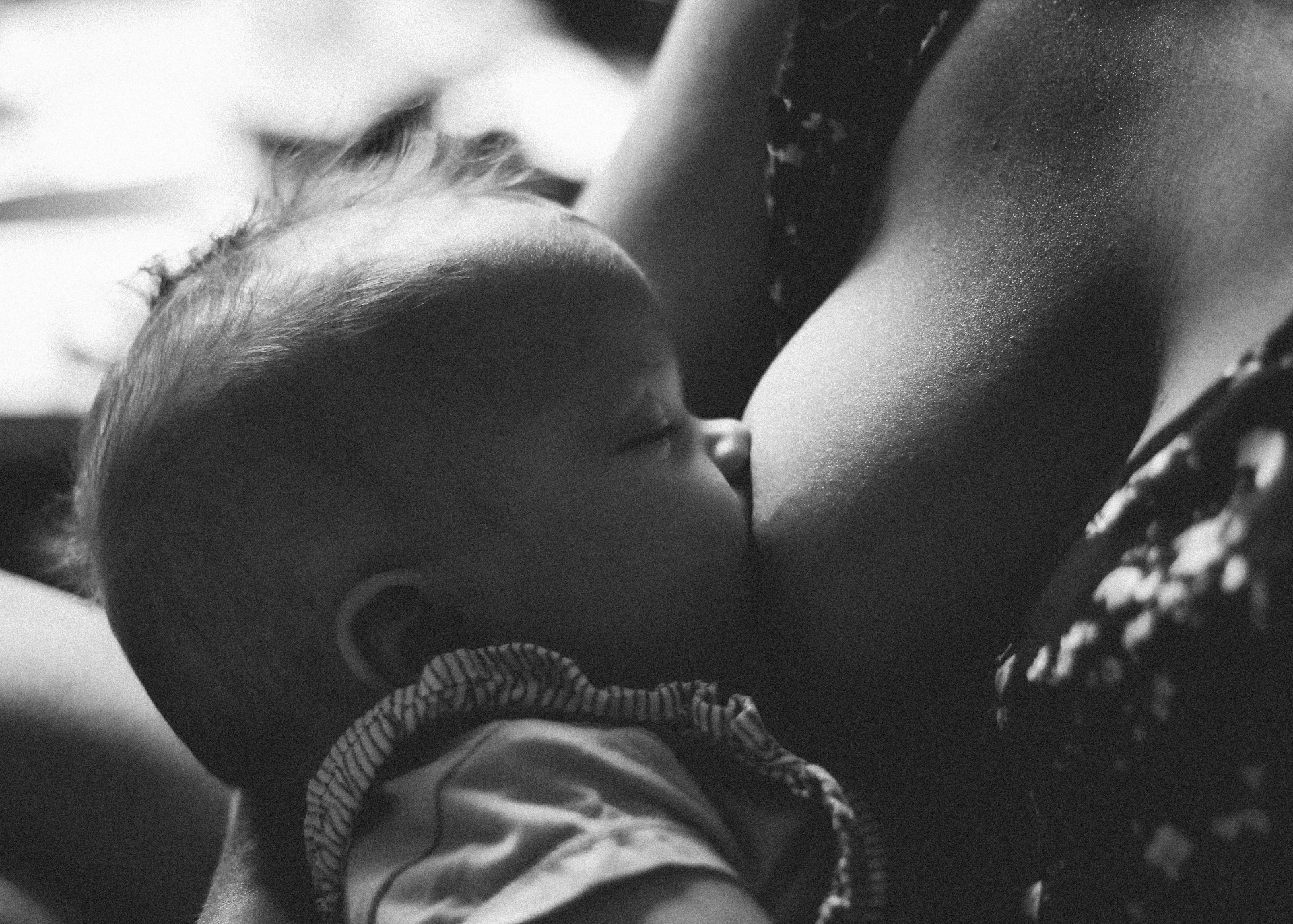 A mother nursing her infant, photographed in soft black and white.